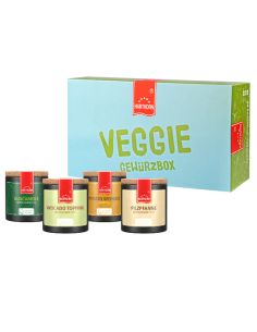 Box mit der Aufschrift ‚Veggie Gewürzbox‘ neben vier schwarzen Pappdosen mit verschiedenfarbigen Etiketten.