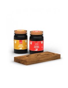 Zwei schwarze Keramiktöpfchen mit den Etiketten „Paprika edelsüß“ (rot) und „Curry Oriental“ (gelb), daneben Holztablett