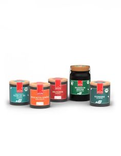 Eine Auswahl von vier bunten Pappdosen mit Korkdeckeln –und einem Keramiktopf.