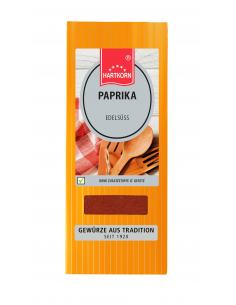 Flachbeutel mit der Aufschrift „PAPRIKA Edelsüß“, daneben hölzerne Kochlöffel auf kariertem Tuch.