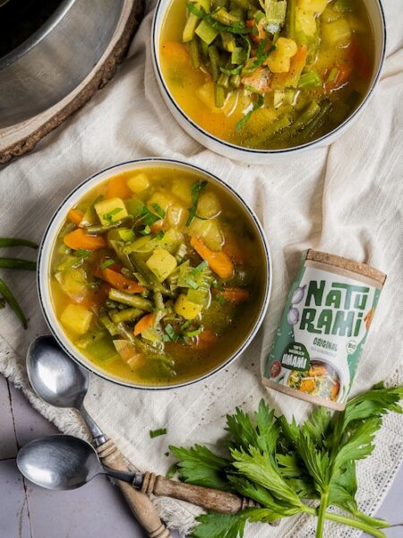 Klare Gemüsesuppe mit grünen Bohnen, Karotten und Kartoffeln in einer weißen Schale, daneben das Naturami Gewürzsalz Original