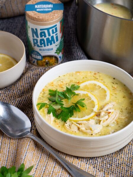 Eine gelbliche Suppe mit Zitrone und Hähnchen, im Hintergrund steht eine Dose Naturami mediterran.