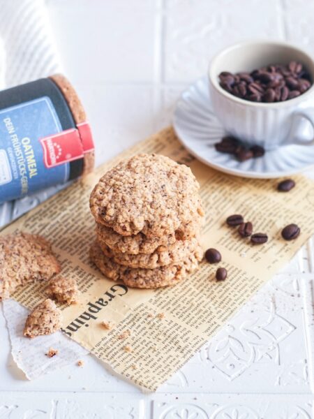 Schwedische Haferkekse auf einem Papier. Im Hintergrund Hartkorn Oatmeal Gewürz und eine Tasse mit Kaffeebohnen.