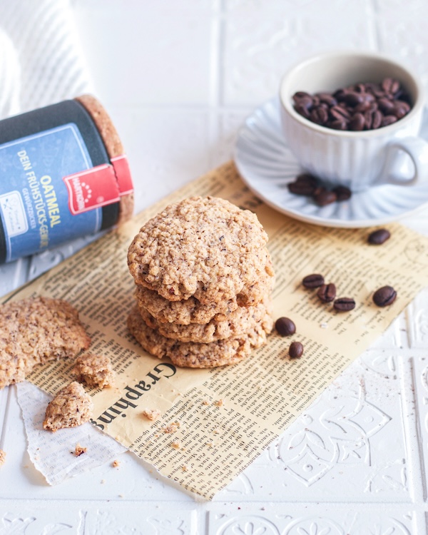 Schwedische Haferkekse auf einem Papier. Im Hintergrund Hartkorn Oatmeal Gewürz und eine Tasse mit Kaffeebohnen.