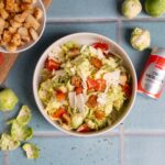 Winter-Caesar-Salat mit Rosenkohl, Parmesan, Croûtons und Chili-Knoblauch-Dressing in einer Schüssel angerichtet