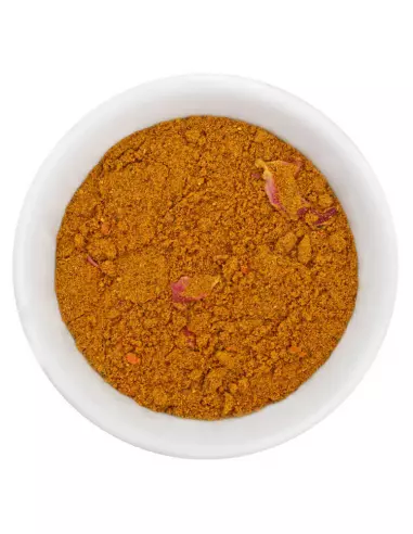 Fein gemahlenes braun-gelbes Ras el Hanout Gewürzpulver mit kleinen Stückchen in weißer Schale, von oben fotografiert