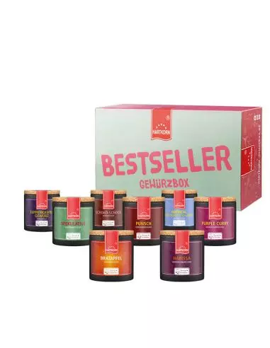 Geschenkbox mit der Aufschrift „Bestseller Gewürzbox“. Davor bunte Pappdosen mit Korkdeckel, die verschiedene Gewürze enthalten.