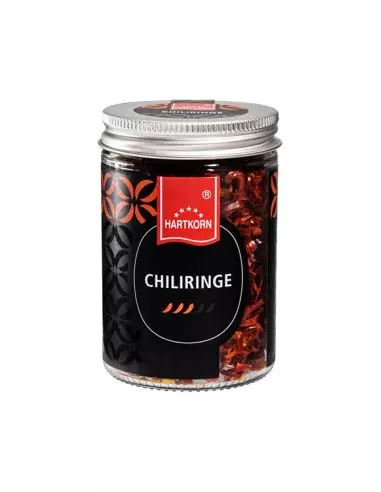 Glas mit getrockneten Chiliringen, silbernem Schraubdeckel und Etikett mit drei stilisierten Chilischoten als Schärfegrad