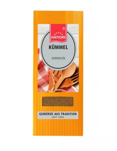 Flachbeutel mit der Aufschrift „Kümmel“, im Hintergrund rot-weißes Tuch und Holzlöffel.